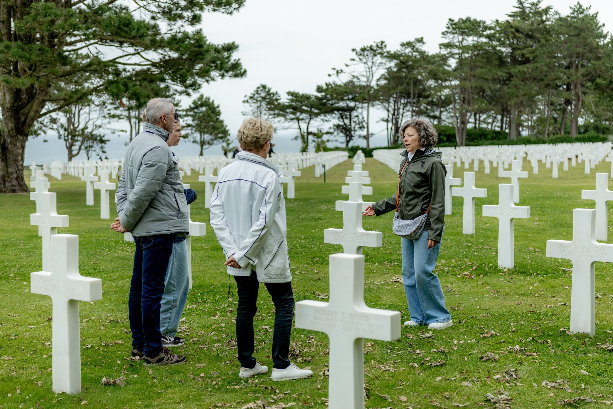 Tour guide leading a small group through the Normandy American Cemetery during a historical guided tour.