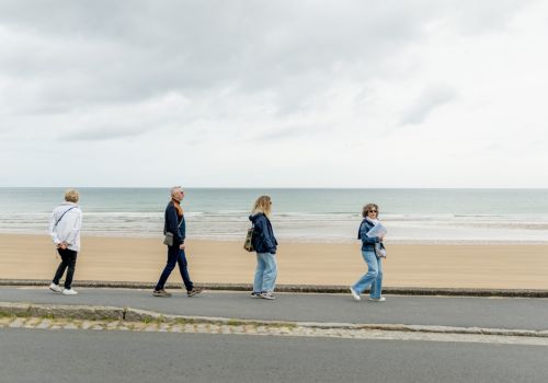 Small group walking along Omaha Beach during a guided Normandy tour.
